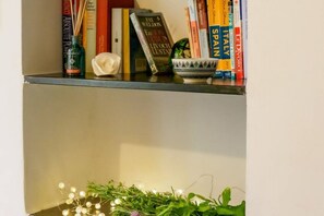 Una estantería con libros, una vela y un cuenco decorativo.