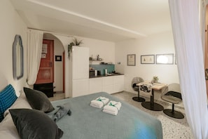 Une chambre d’hôtel de taille réduite comprenant un lit, une petite kitchenette, un coin repas et une salle de bain.