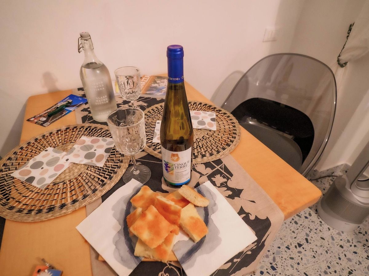 Une table avec une bouteille de vin, des verres et une assiette de pain.