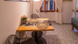 A dining area with a table, chairs, a vase with flowers, a lamp, and a window with curtains. - Rissu Nice Studio in Vernazza (Vernazza)