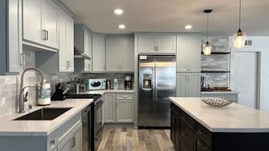 A modern kitchen with light gray cabinets, stainless steel appliances, and a central island. - Newport Beach Balboa House with Large Patio, Walk to Lido Village (Newport Beach)