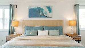 A bedroom with a large bed, two nightstands, a headboard, and a painting of a surfer on a wave. - Newport Beach Balboa House with Large Patio, Walk to Lido Village (Newport Beach)