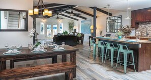 Une cuisine spacieuse dotée d’un îlot central, de tabourets de bar et d’un coin repas avec un banc en bois.