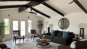 A spacious living room with a high ceiling, a round coffee table, a sofa, and two chairs. - Newport Beach Balboa House with Large Patio, Walk to Lido Village (Newport Beach)
