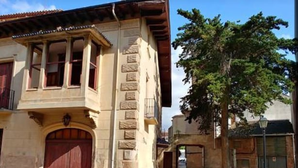 Un edificio de dos pisos con una gran puerta de madera y un balcón.
