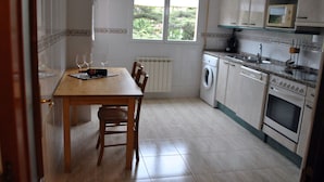 Cocina compacta con mesa de comedor, sillas, lavadora y microondas.