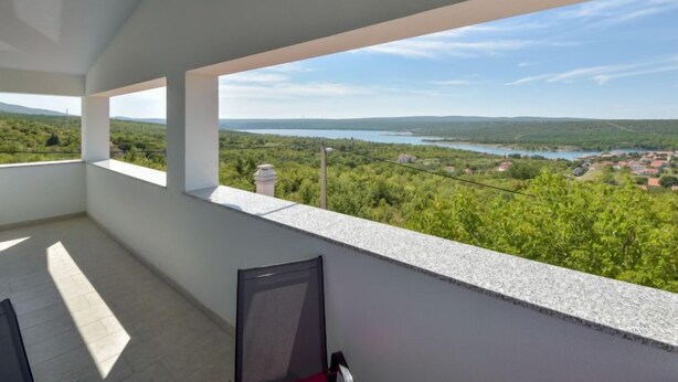Ein Balkon mit Blick auf einen See und umliegendes Grün.