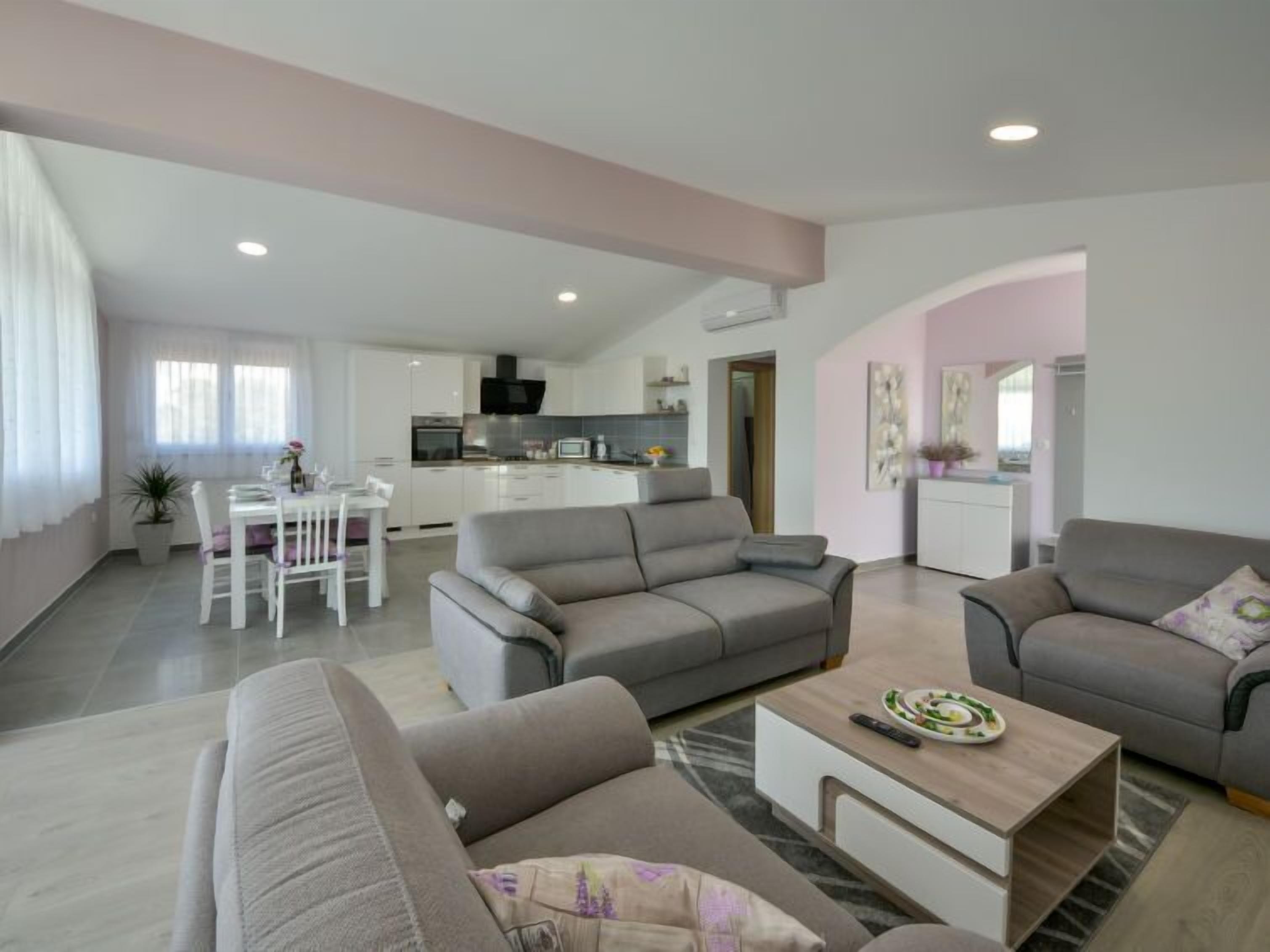 Ein modernes Wohnzimmer mit zwei Sofas, einem Couchtisch und einem Essbereich mit Tisch und Stühlen.