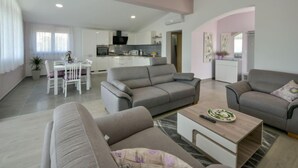 Ein modernes Wohnzimmer mit zwei Sofas, einem Couchtisch und einem Essbereich mit Tisch und Stühlen.