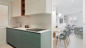Et moderne køkken med en central ø, indbyggede skabe og et spiseområde med bord og stole.
