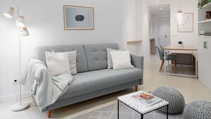 En moderne stue med en grå sofa, et sofabord og et spiseområde.