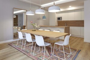 A modern dining area with a wooden table, white chairs, and pendant lighting.