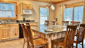 Una cocina con armarios de madera, encimera de granito y un comedor con sillas de madera.
