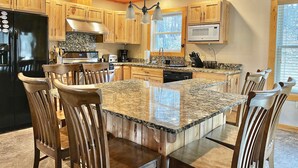 Una cocina amplia con gabinetes de madera, encimeras de granito y una isla central con asientos.