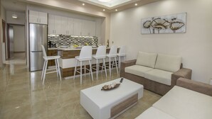 A modern kitchen with white cabinets, a stainless steel refrigerator, and a dining area with white chairs. - Spacious & convinient place near Acropolis Museum (Athina)