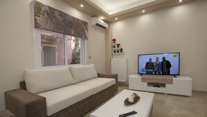 A modern living room with a beige sofa, a white coffee table, and a flat-screen TV on a white stand. - Spacious & convinient place near Acropolis Museum (Athina)