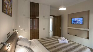 A hotel room with a bed, a TV mounted on the wall, and a wardrobe. - Spacious & convinient place near Acropolis Museum (Athina)