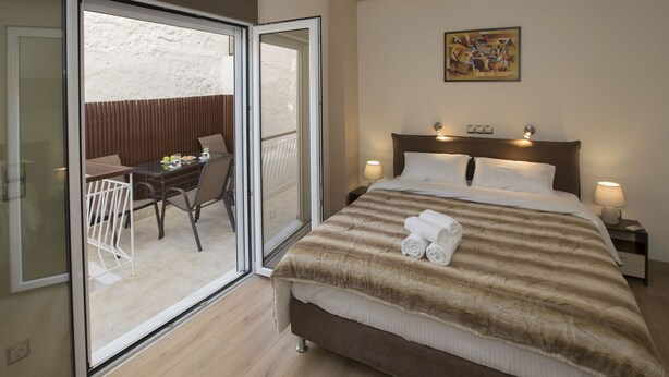 A hotel room with a bed, a balcony with a table and chairs, and a painting on the wall. - Spacious & convinient place near Acropolis Museum (Athina)