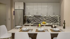 A modern kitchen with white cabinets, a tiled backsplash, and a central island with seating. - Spacious & convinient place near Acropolis Museum (Athina)