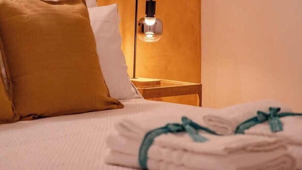 A neatly made bed with a folded towel and a pillow. - Petrella's Point Studio (Vernazza)