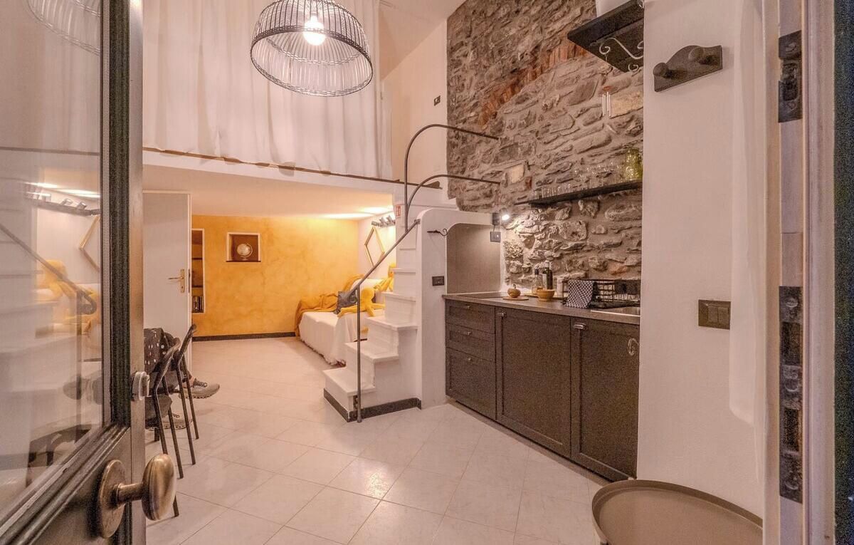 Une cuisine moderne avec un mur d’accent en pierre, un four encastré et un coin repas avec un escalier menant au salon.
