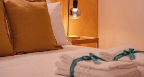 A neatly made bed with a folded towel and a pillow. - Petrella's Point Studio (Vernazza)