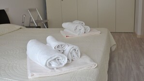 Ein Hotelzimmer mit einem ordentlich bezogenen Bett, einem Sessel und einem Kleiderschrank.