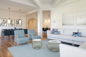 A modern living room with a sofa, chairs, and round coffee tables.