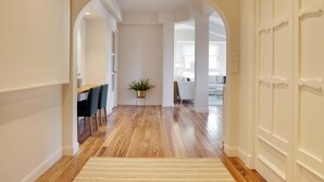 A hallway with wooden flooring, a dining area with chairs and a table, and a potted plant.