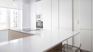 A modern kitchen with white cabinetry, a stainless steel range hood, and a built-in microwave.
