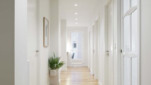 A hallway with wooden flooring, white walls, and doors leading to other rooms.