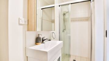 A modern bathroom with a white sink, a mirror, and a glass-enclosed shower.
