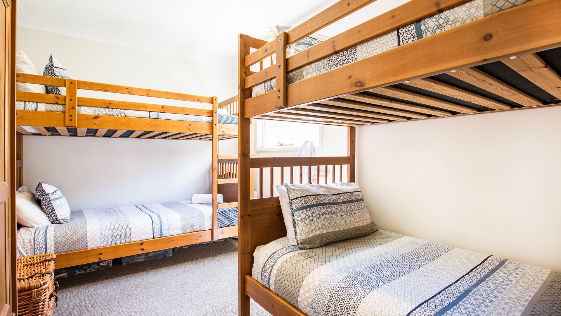 Ein Schlafsaalzimmer mit Etagenbetten, einem Fenster und einem Korbwäschekorb.