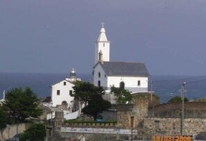 A white church with a bell tower, surrounded by stone walls and trees. - Apartamentos Jesús for 4 people (Valdés)