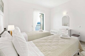 A hotel room with two beds, a dresser, a mirror, and a view of the balcony.