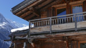 Un chalet en bois doté d’un balcon donnant sur une montagne enneigée.