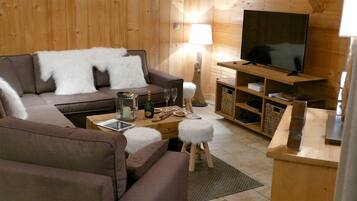 A cozy living room with a sofa, a coffee table, a TV, and a lamp.