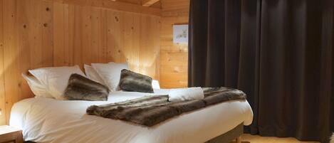Un dormitorio de estilo cabaña de madera con cama, almohadas y una manta de piel.