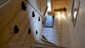 Un escalier en bois orné de découpes en forme de cœur, menant à une pièce dotée d’une fenêtre.