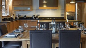 Une cuisine moderne avec des meubles en bois, une table à manger pour six personnes et un grand four.