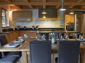 Une cuisine moderne avec des meubles en bois, une table à manger pour six personnes et un grand four.