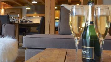Un'accogliente stanza con travi in legno, un'area pranzo con sedie e un tavolo, e una bottiglia di vino sul tavolo.