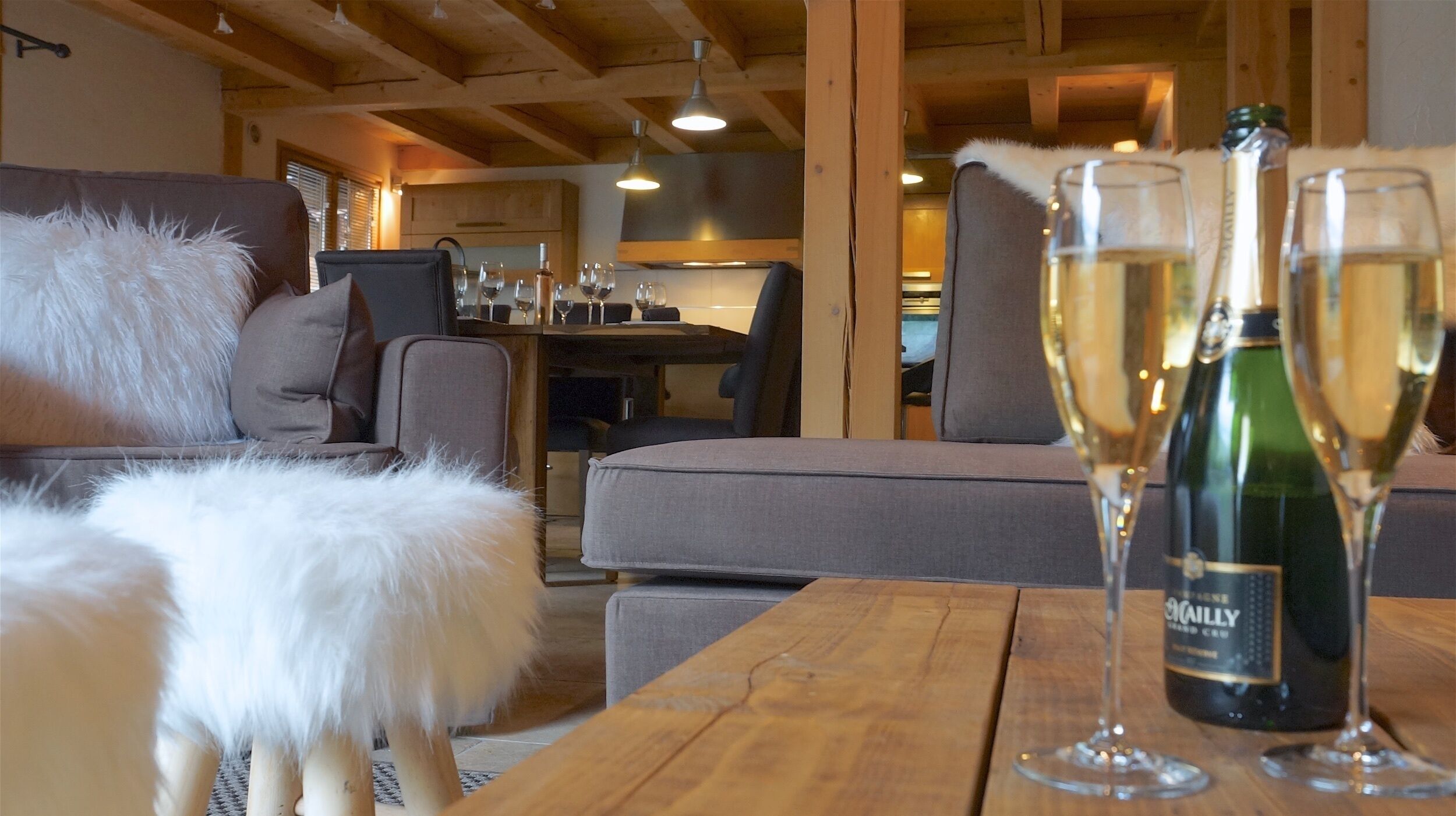 Un salon chaleureux avec une table en bois, un chien blanc au pelage doux et une bouteille de vin.
