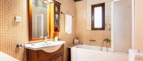 A bathroom with a wooden vanity, a bathtub, and a toilet.