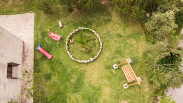Vue aérienne d’une cour intérieure avec un mur en pierre, un motif circulaire en pierre et un banc en bois.