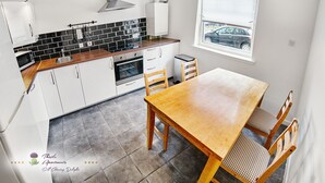 Una cocina moderna con armarios blancos, encimera de madera y ventana con vistas a la calle.