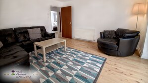 Una sala de estar con sofá, sillón reclinable, mesa de centro y alfombra estampada.
