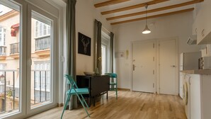 A modern kitchen with wooden flooring, a dining area with teal chairs, and large windows offering a view of the city. - Balcones de CANDELARIA by Cadiz4Rentals (Cádiz)