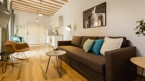 A modern living room with a sofa, rocking chair, and coffee table. A kitchen area is visible in the background. - Balcones de CANDELARIA by Cadiz4Rentals (Cádiz)