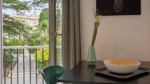 A balcony with a view of a street and greenery, a table with a bowl and vase, and a chair. - Balcones de CANDELARIA by Cadiz4Rentals (Cádiz)